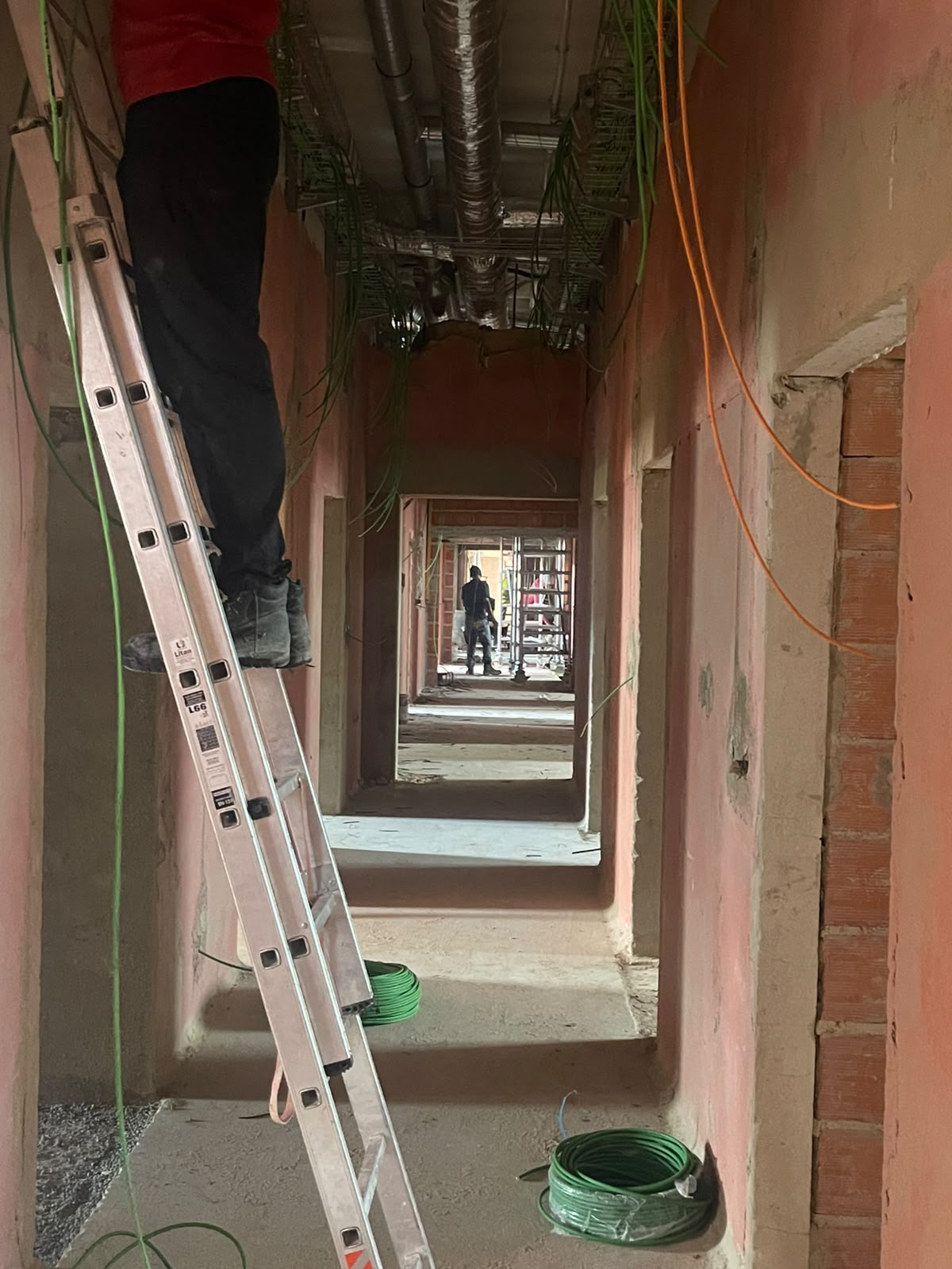 Corredor em obra com instalações elétricas e AVAC em execução